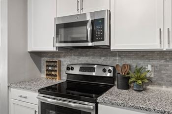 A modern kitchen with a black stove top oven and a microwave above it.